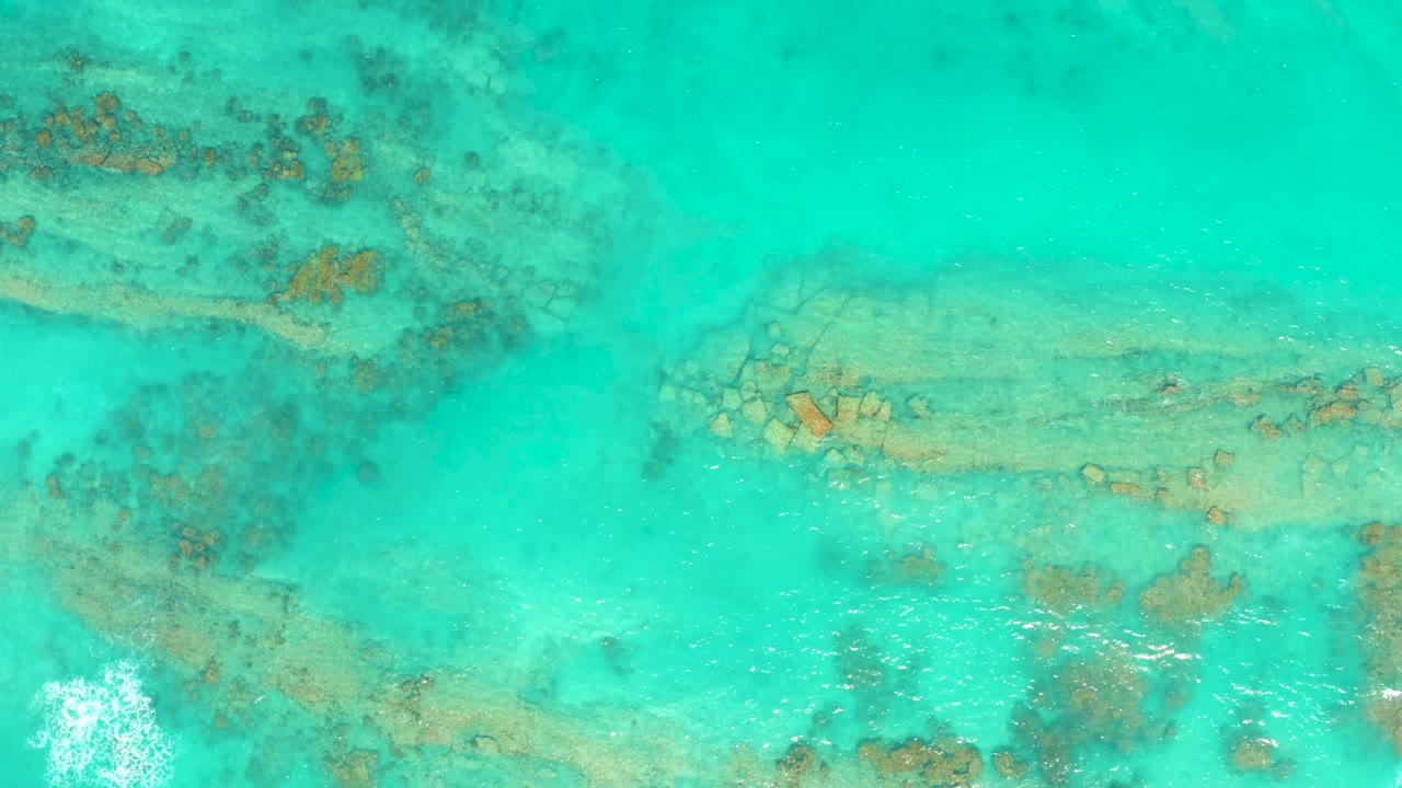 Clear ocean surface with coral patches beneath.