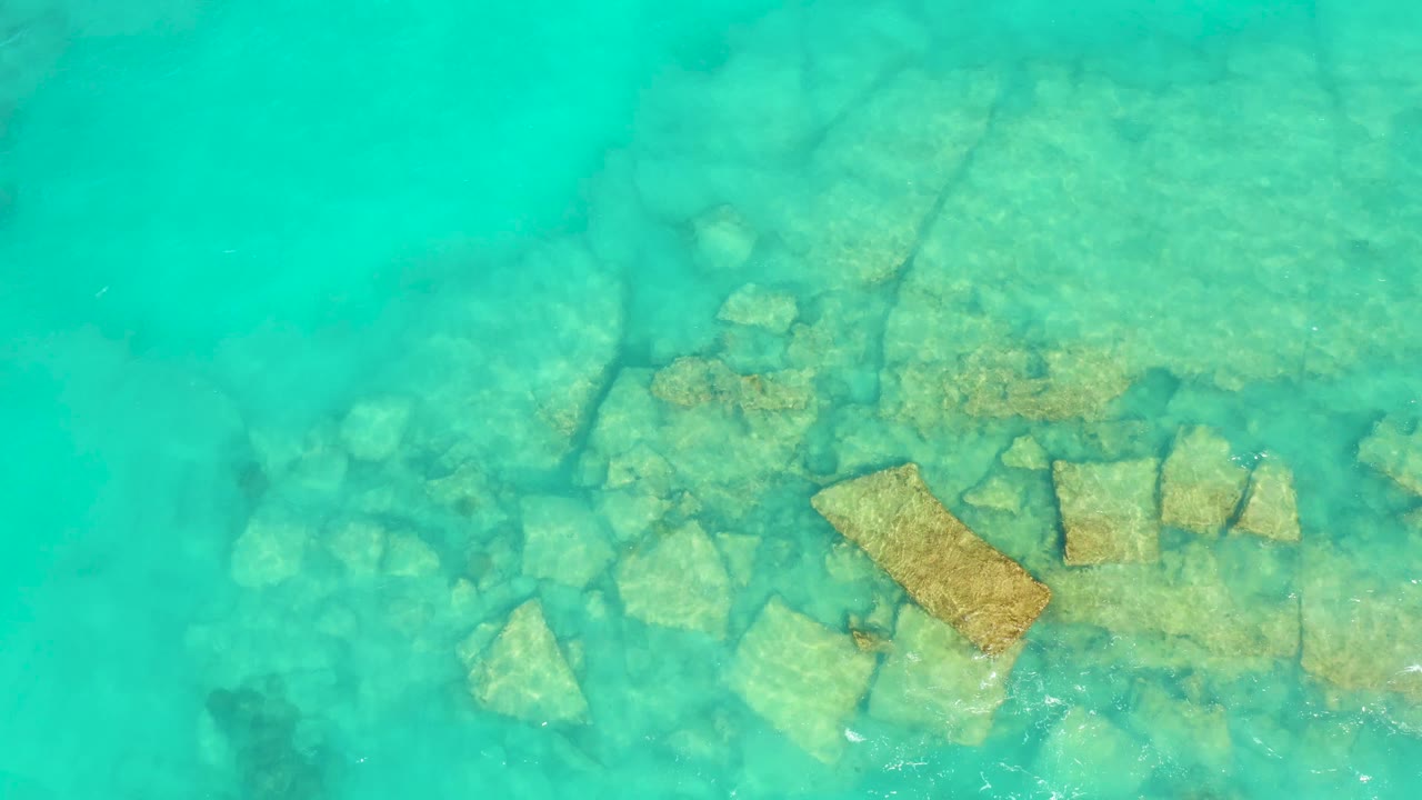 Submerged rocks under calmer turquoise water