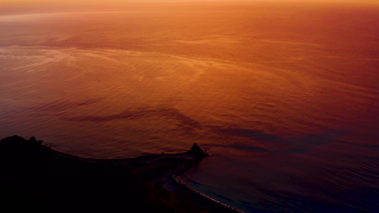 At 0:01, the orange reflection covers more of the visible ocean surface while the Cabo Pulmo coastline remains a dark shape along the bottom with no visible people.
