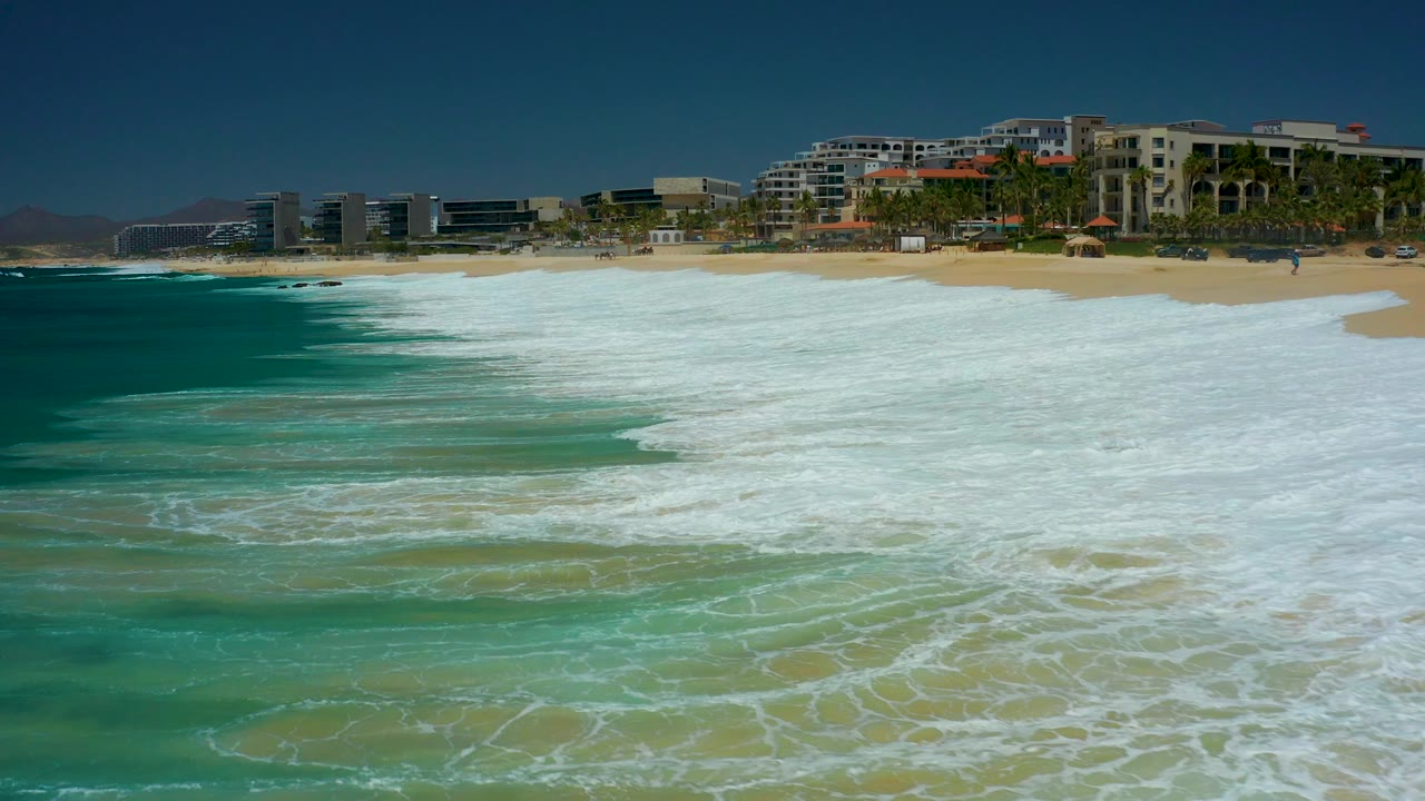 Wide shoreline view with foam spreading across turquoise water.
