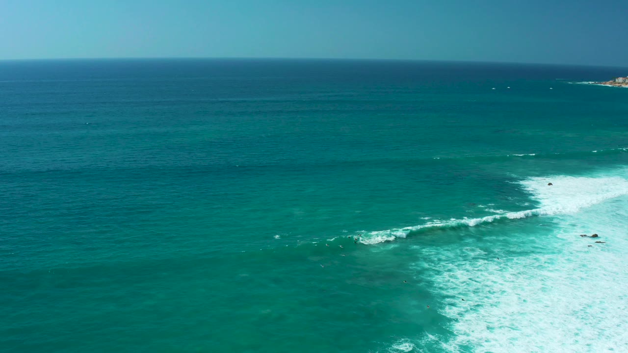 Turquoise ocean with a white breaking wave and distant horizon.