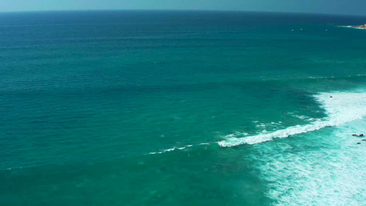 Aerial Marquis Los Cabos ocean view with the horizon high in frame and a white surf break curling through the lower right, with no visible people.