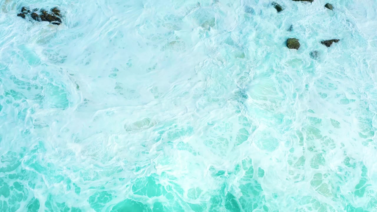 Overhead turquoise surf and white foam with dark rocks near the top edge.
