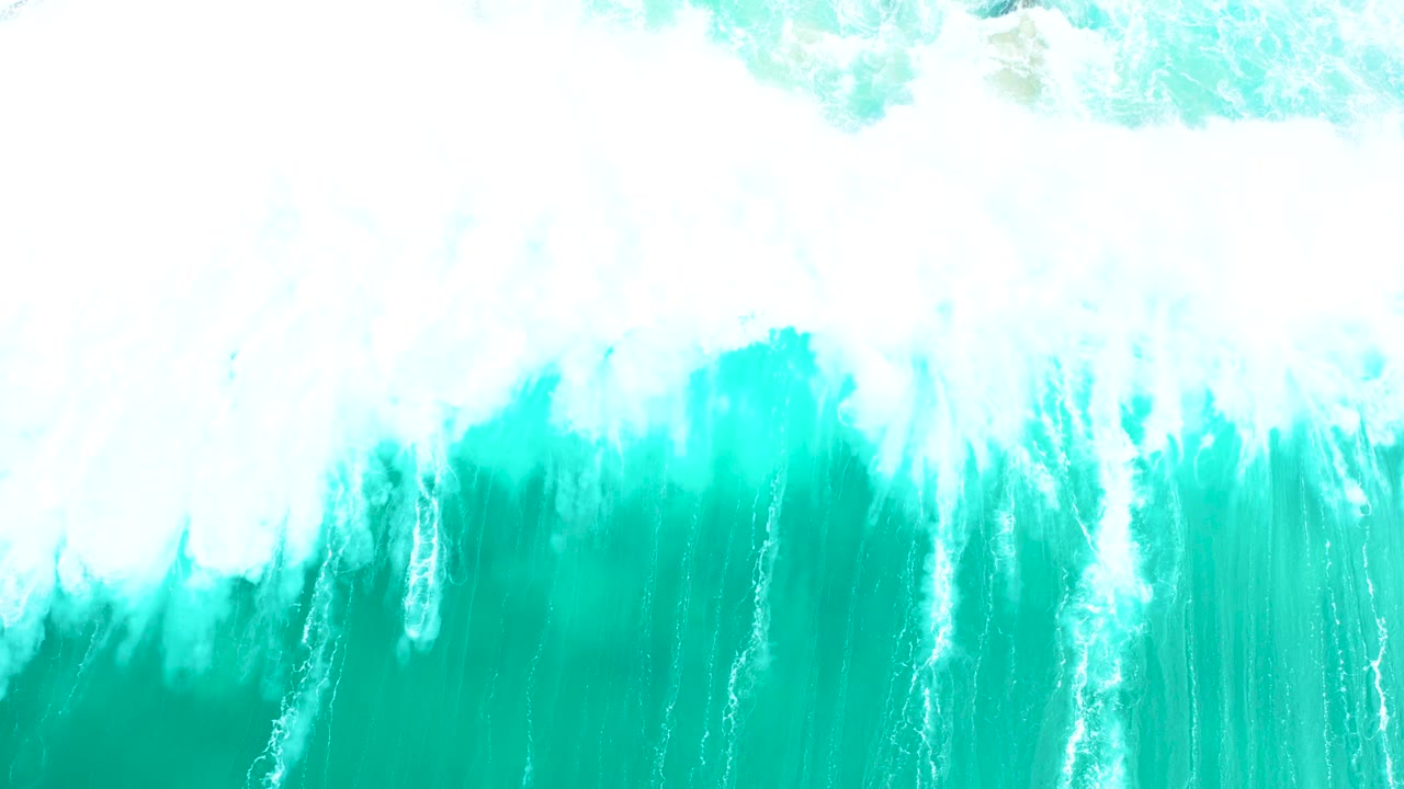 Overhead view at Marquis Los Cabos, Mexico, where a band of white surf foam spreads across bright turquoise water with no visible people.