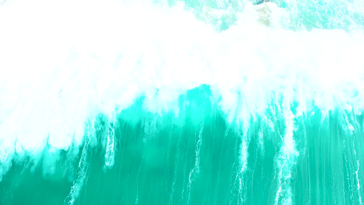 Aerial frame from Marquis Los Cabos, Mexico, showing dense white foam spilling downward over turquoise ocean water with no visible people.