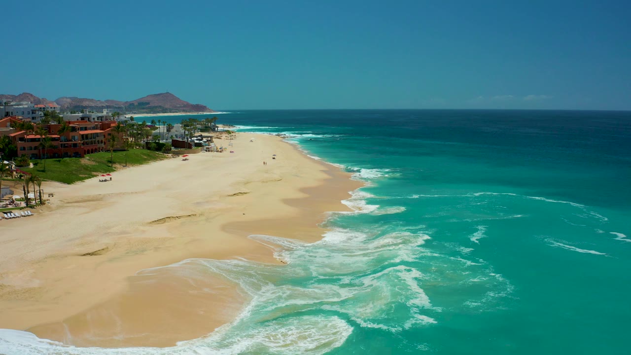 Wide beach and ocean view with foam lines along the shore.