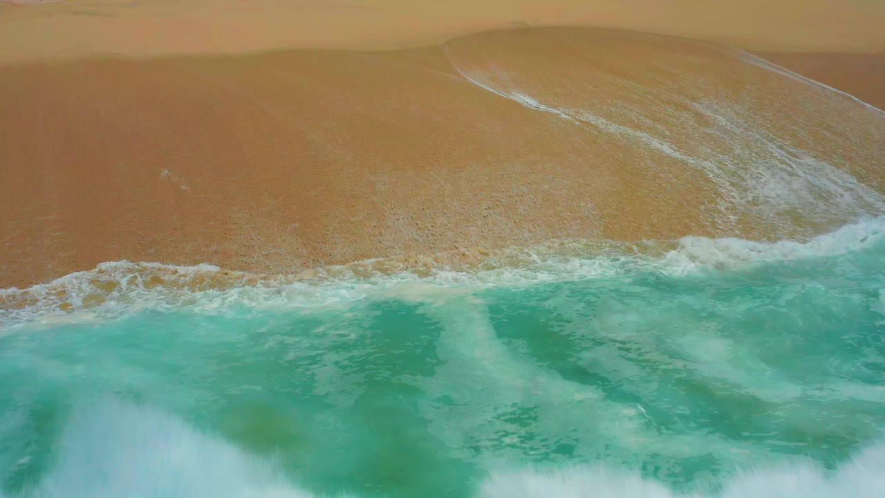 Overhead turquoise wave approaching tan sand