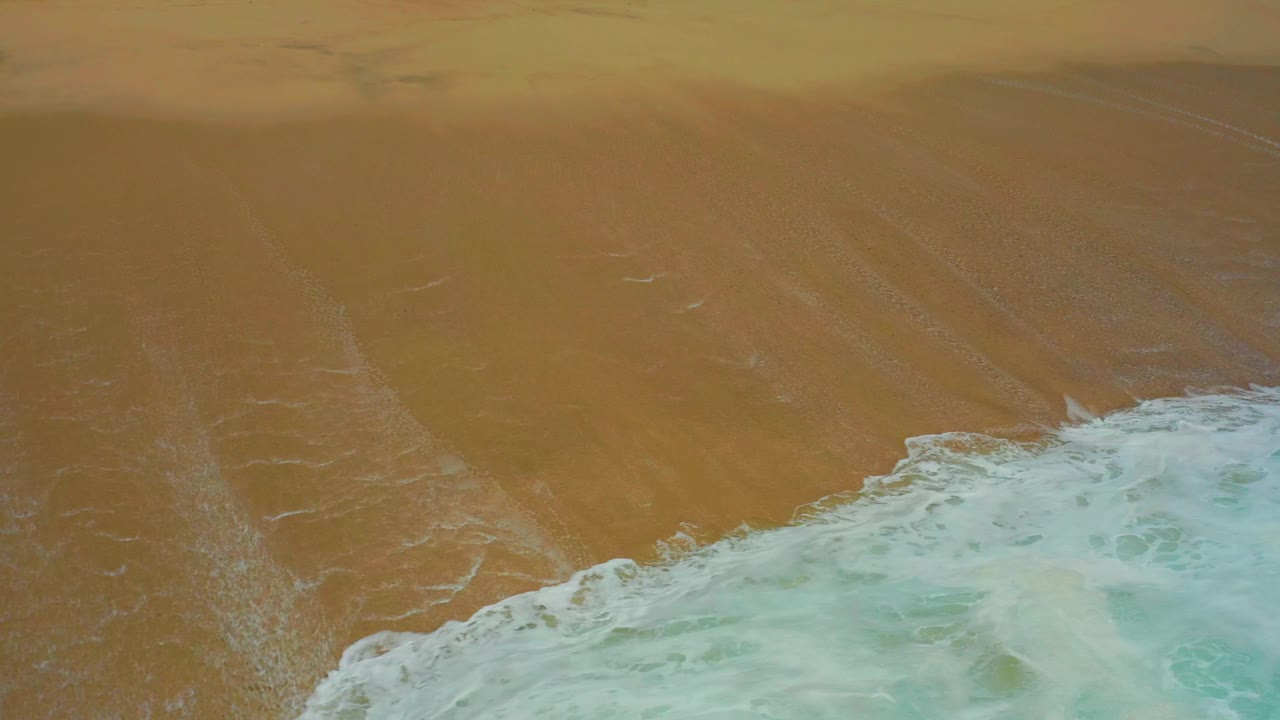 The surf line sits lower in the frame, exposing more broad wet sand above it at the Dreams Los Cabos beach, with no visible people or structures.