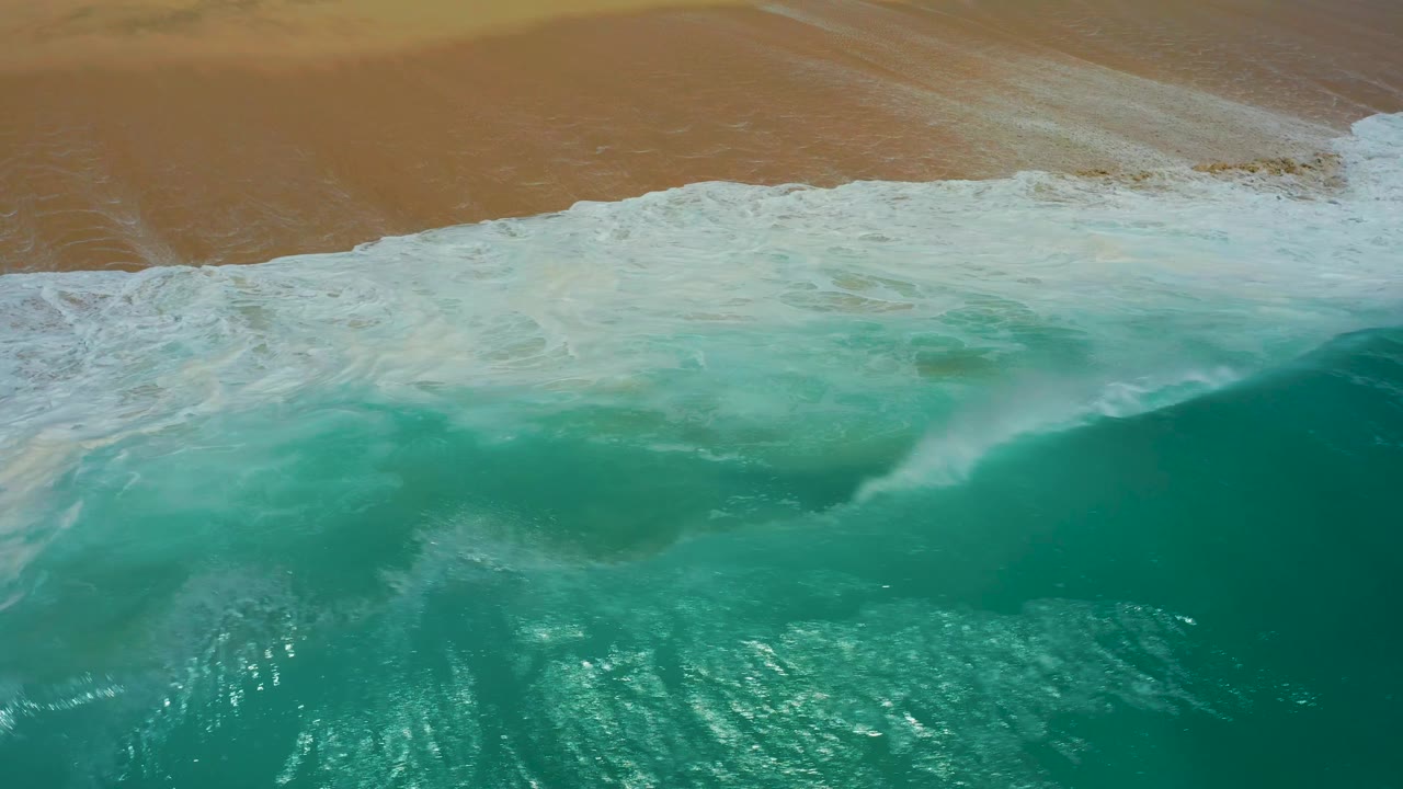 Large turquoise wave cresting near beach
