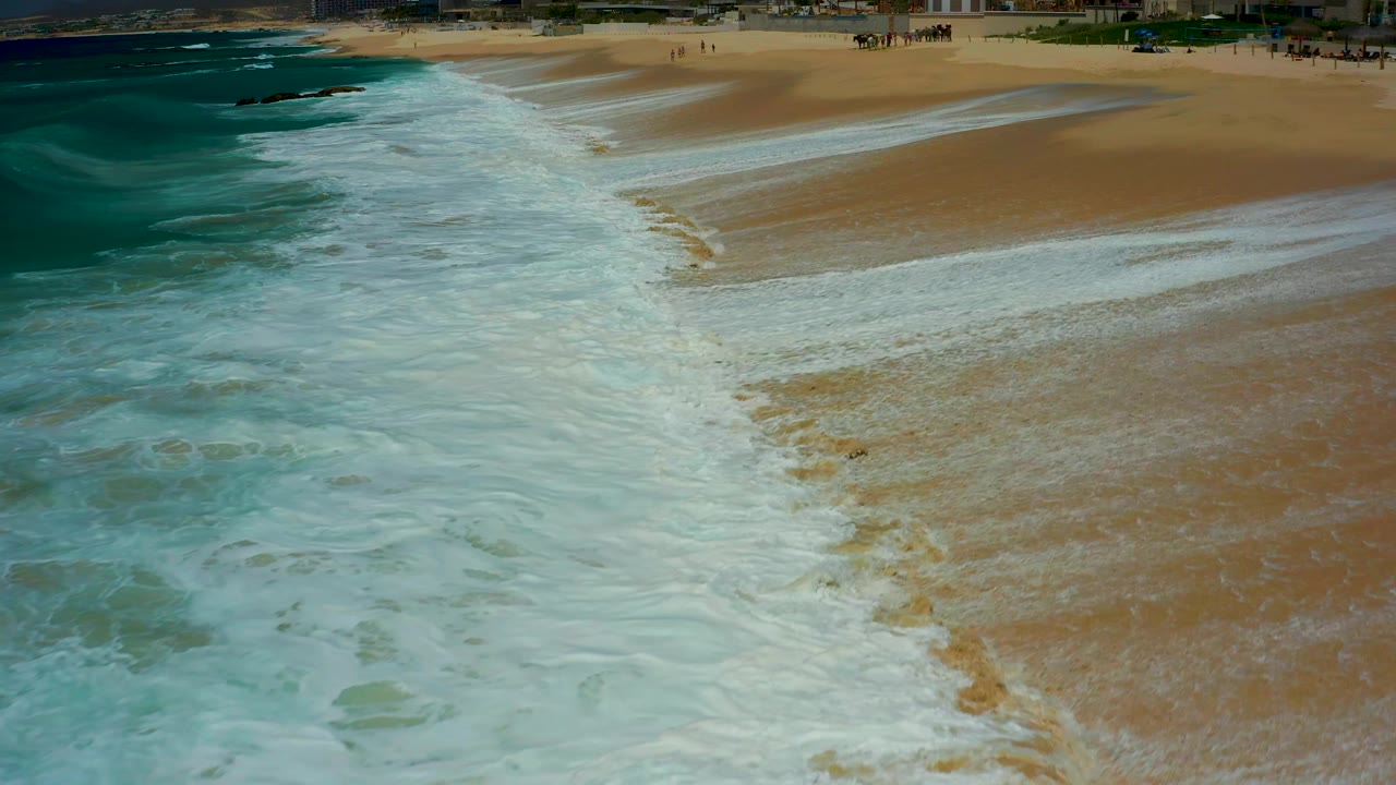 Wide wash of white surf crossing a sandy shoreline.