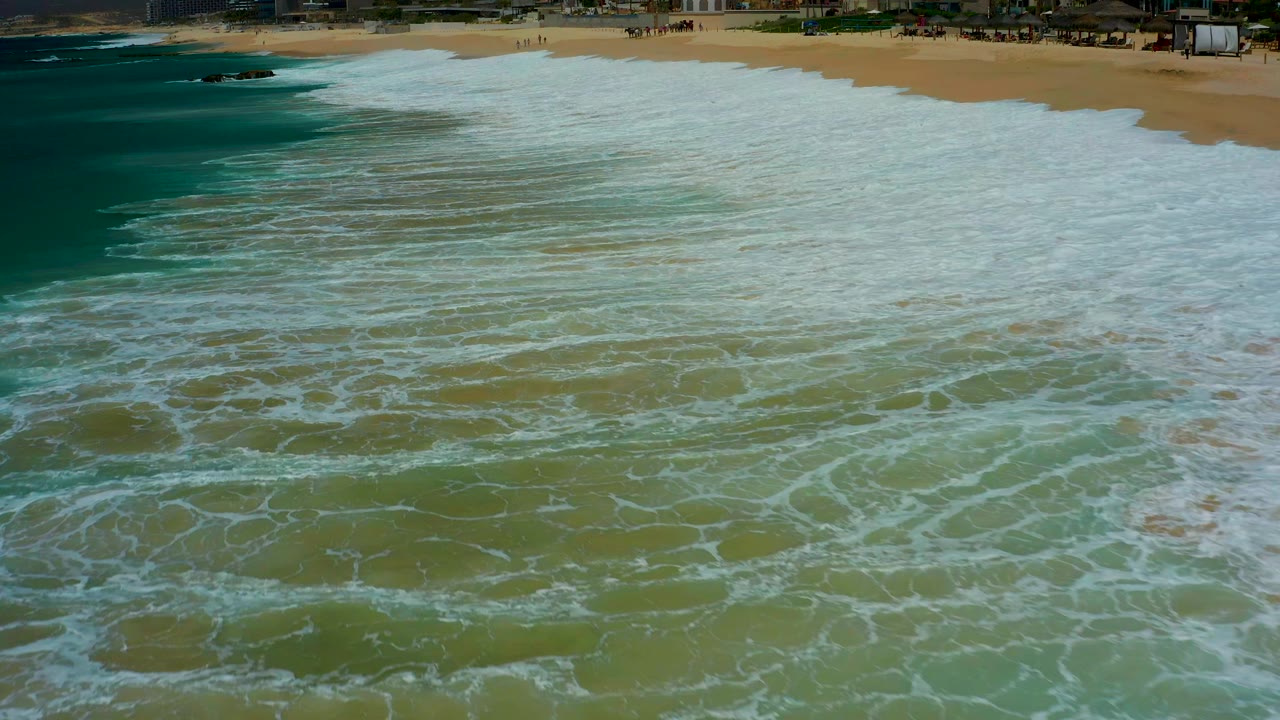 Wide sheet of white foam crossing shallow green water