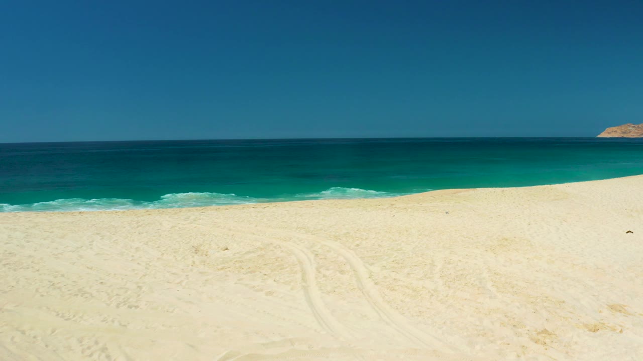 At 0:03, white surf begins to show along the lower ocean edge, with a small headland near the right side of the horizon and no visible people.