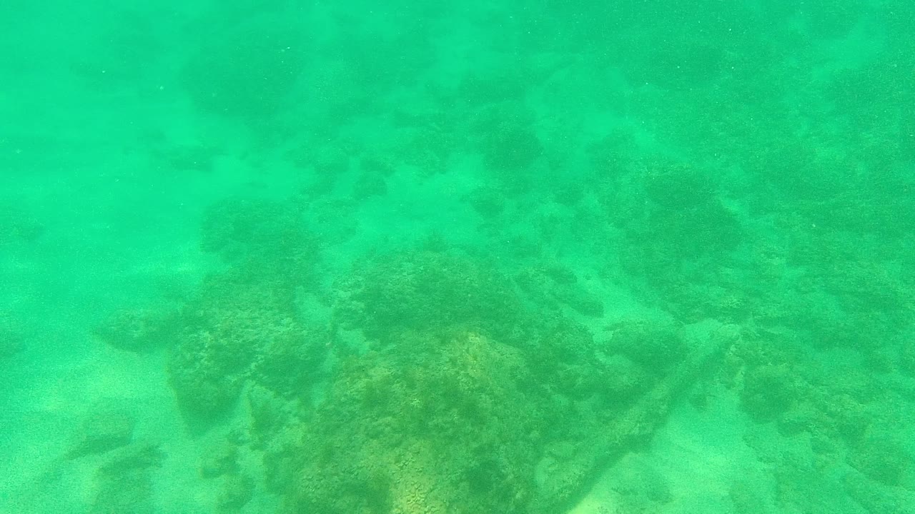 Turquoise underwater view over a rocky seabed and pale sand in Palmilla Los Cabos, Baja California Sur, with no visible people.
