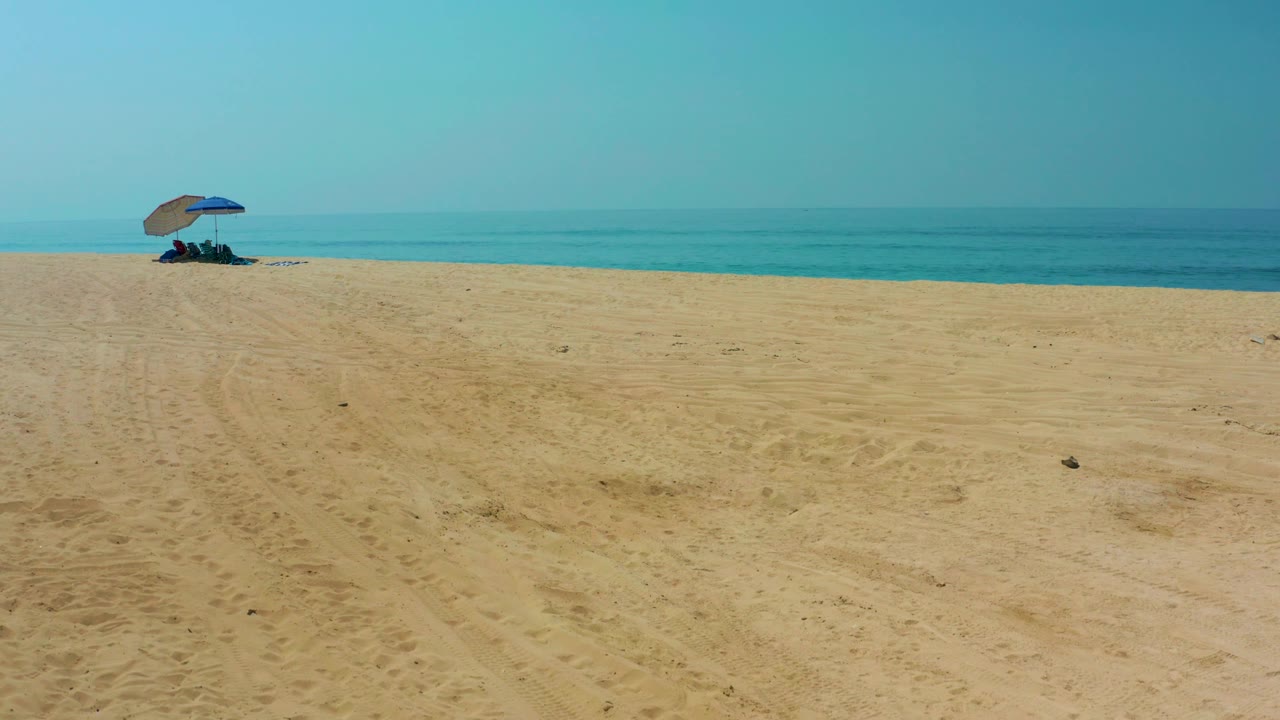 Blue umbrella on quiet beach with ocean in background