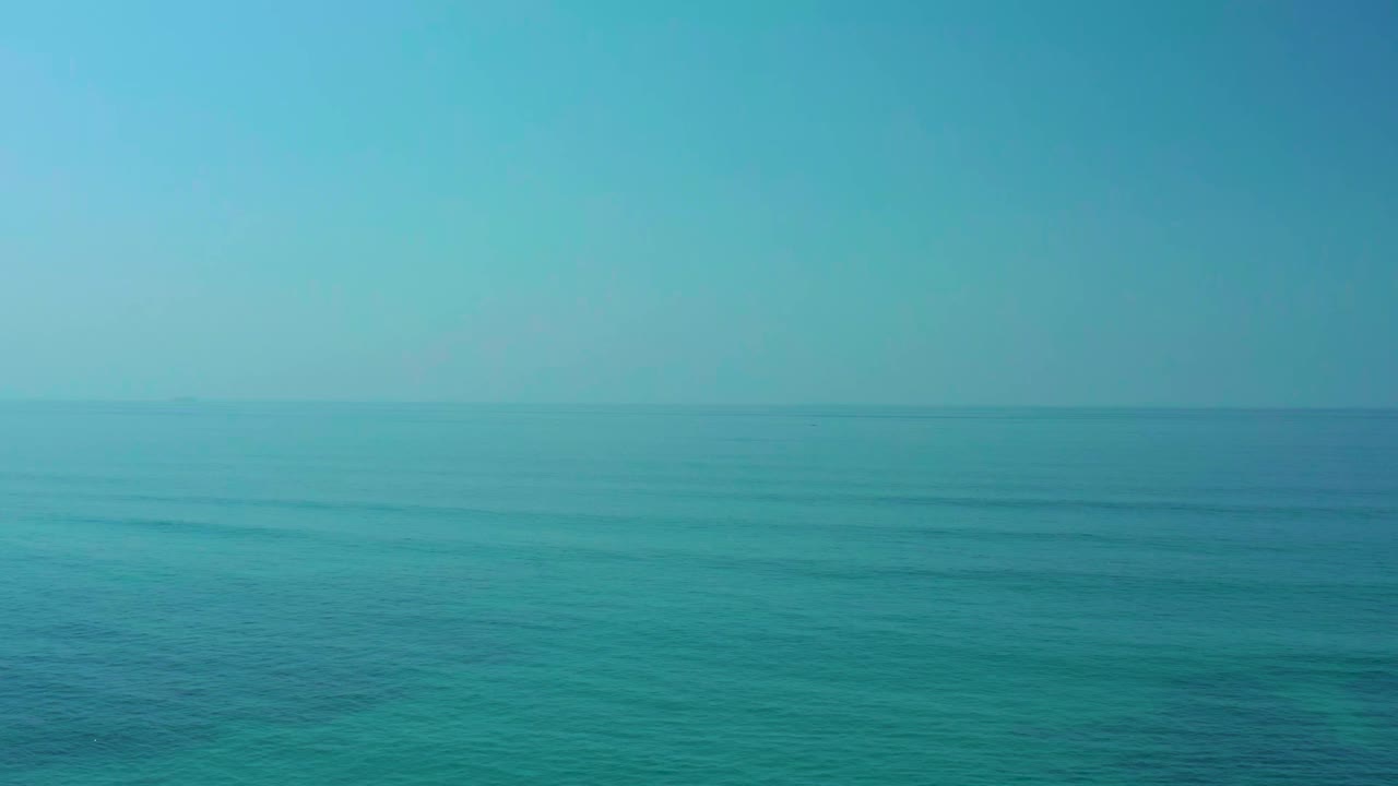 Wide open ocean at Shipwrecks Los Cabos, Baja California Sur, with turquoise water, pale sky, faint horizon detail, and no visible people.
