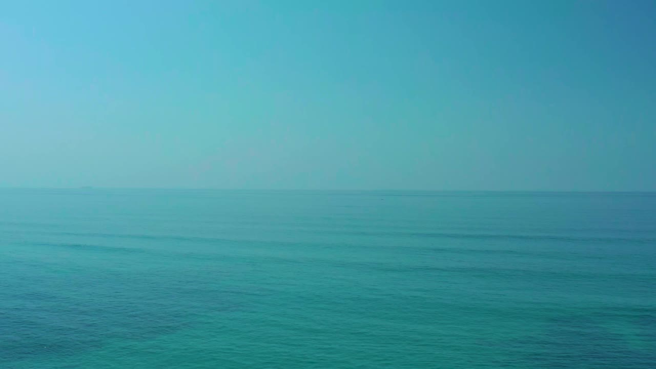 Calm blue-green ocean at Shipwrecks Los Cabos with subtle wave lines across the water, a clear sky, and no visible people.
