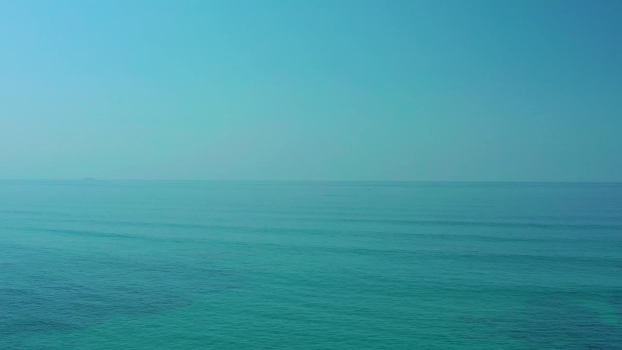 Open sea near Shipwrecks Los Cabos with a hazy horizon, muted turquoise water, faint surface patterns, and no visible people.