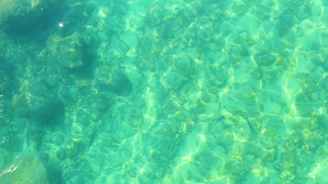 Aqua water surface with darker underwater shapes and small highlights.