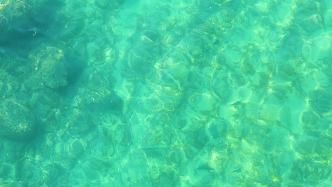 Sunlit ripples crossing shallow blue-green water.