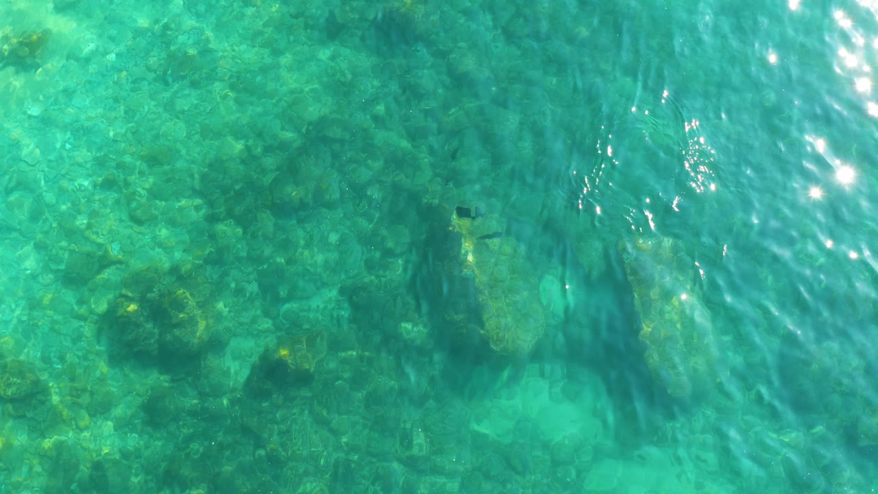 Turquoise water over rocky seabed with sun ripples