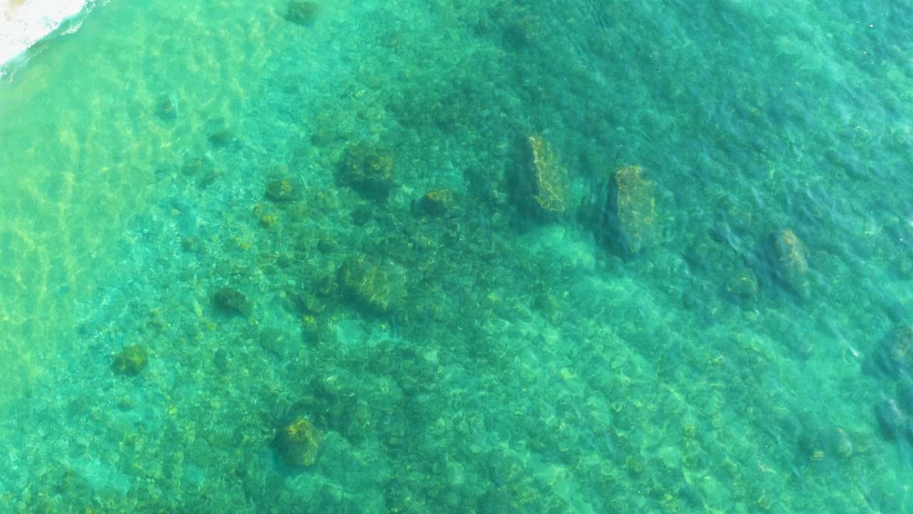 Overhead turquoise water with rocks visible below the surface.