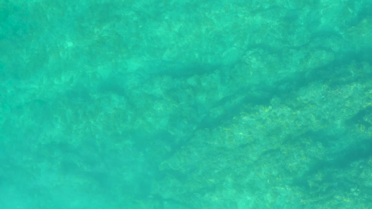 Turquoise shallow water over a rocky seabed.