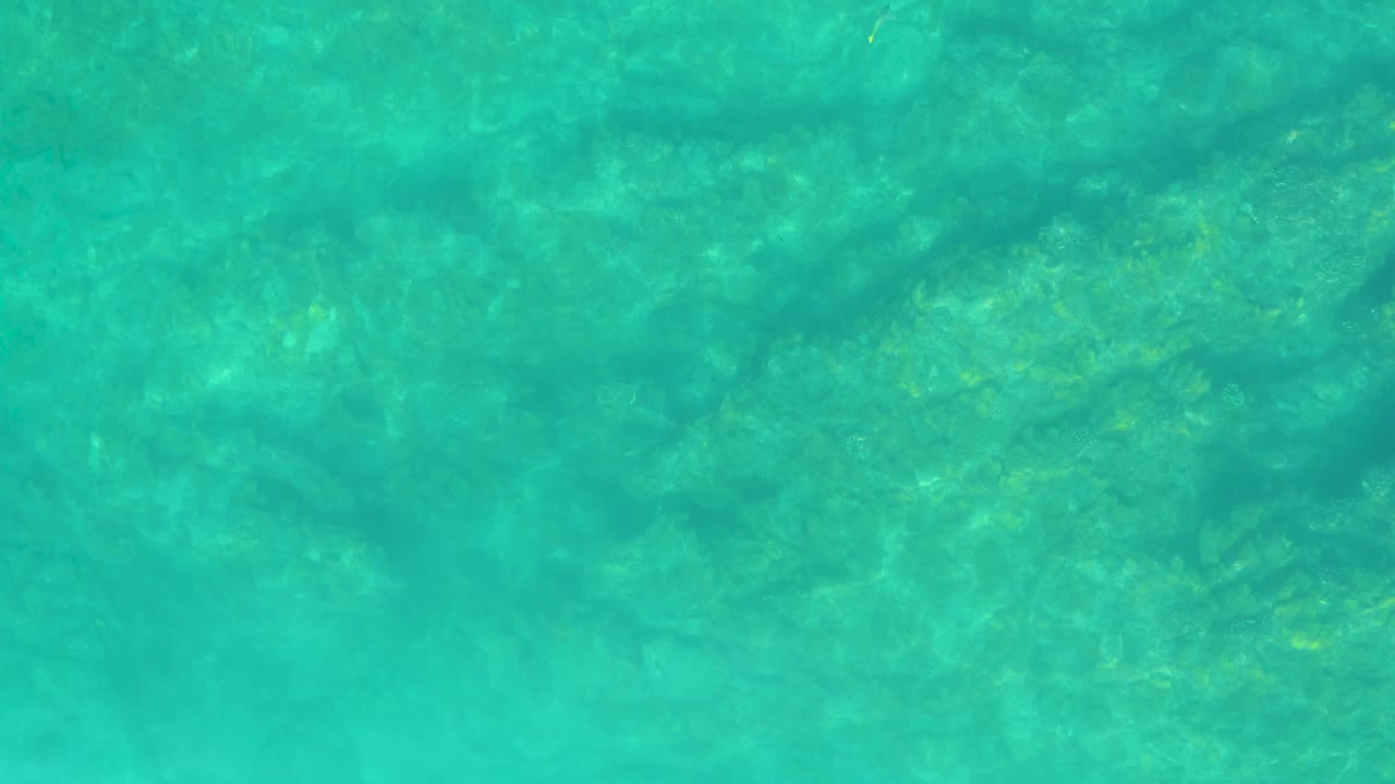 Blue-green shallow ocean water at Shipwrecks Los Cabos shows slightly darker submerged patches under a transparent rippled surface with no visible people.