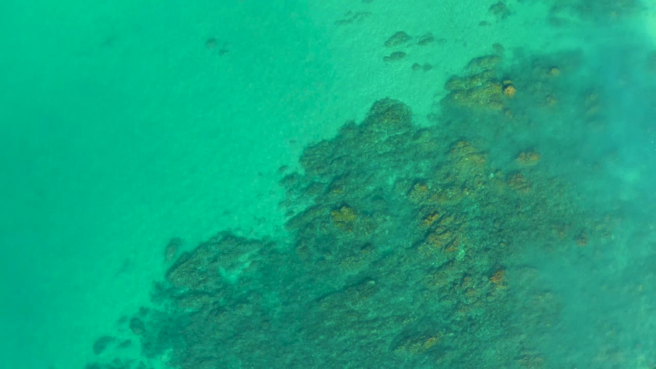 Clear green-blue water above reef and sand