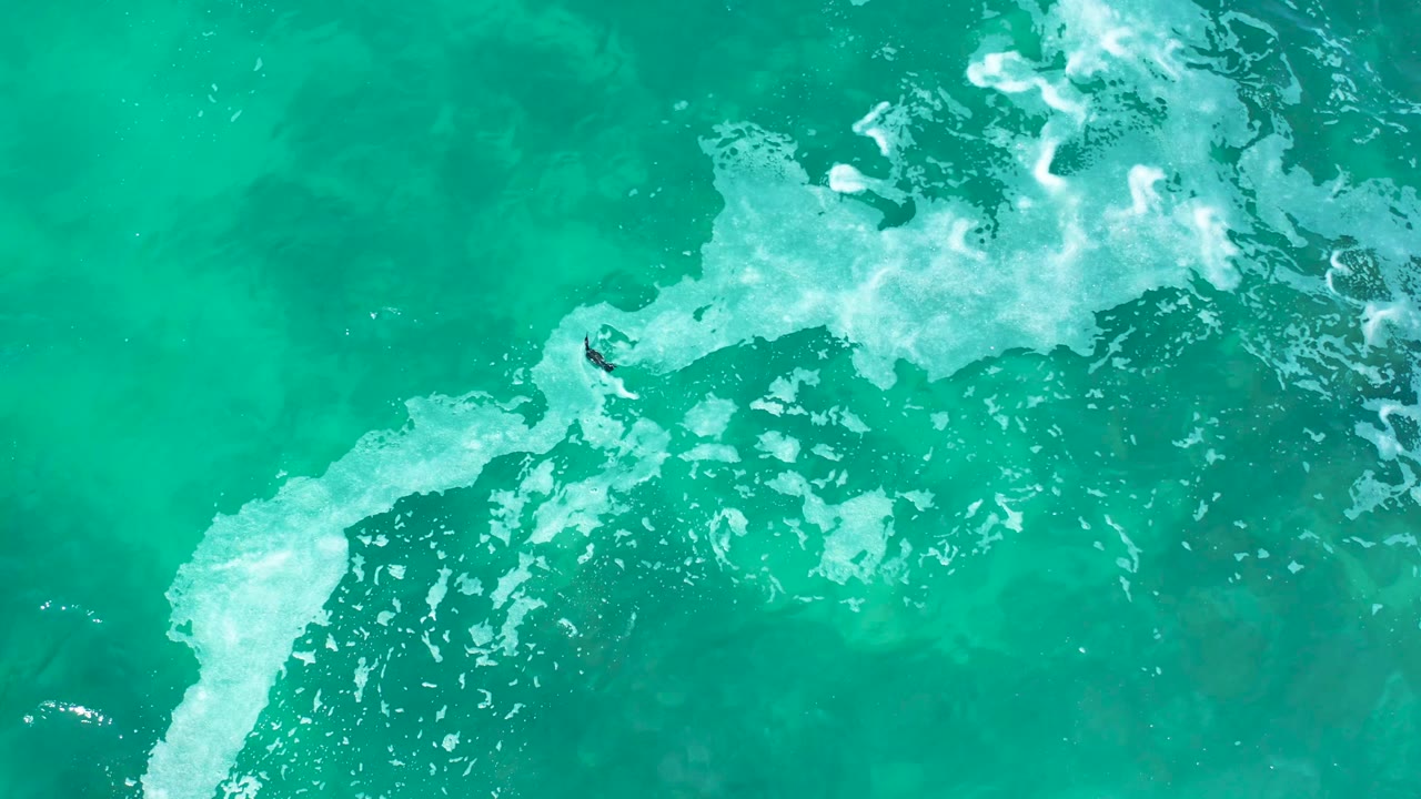 Turquoise water and foamy surf with the bodyboarder near the center area.