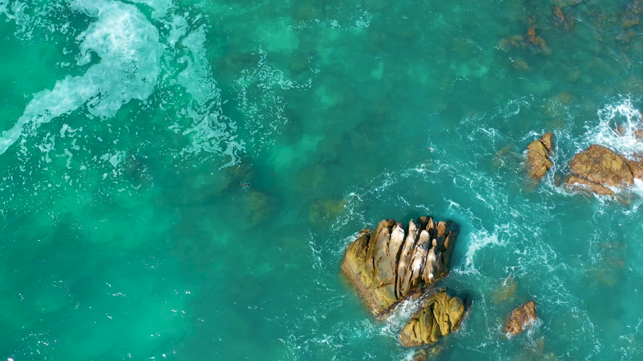 Turquoise ocean waves breaking around rocky outcrops