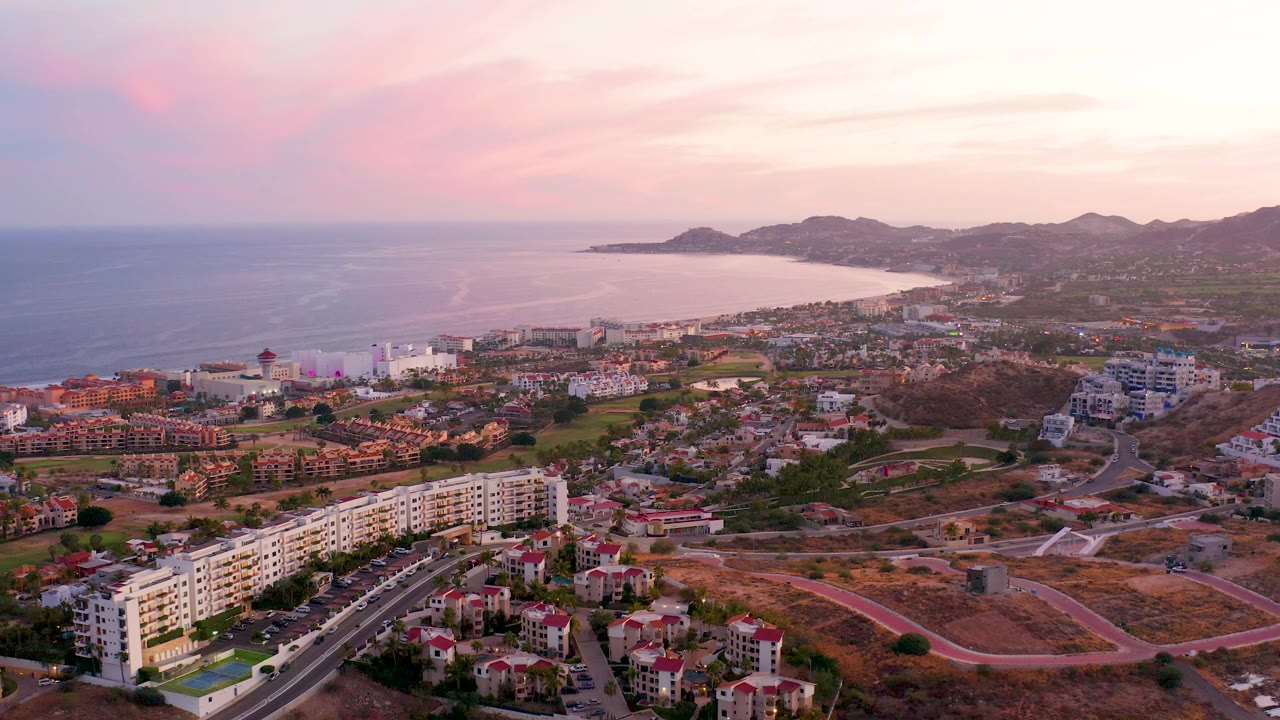 Aerial dusk view of San Jose del Cabo with ocean, hillside development, roads, and homes.