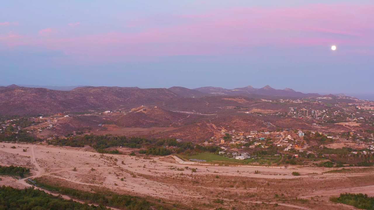 Aerial desert valley view with pink sky and moon.