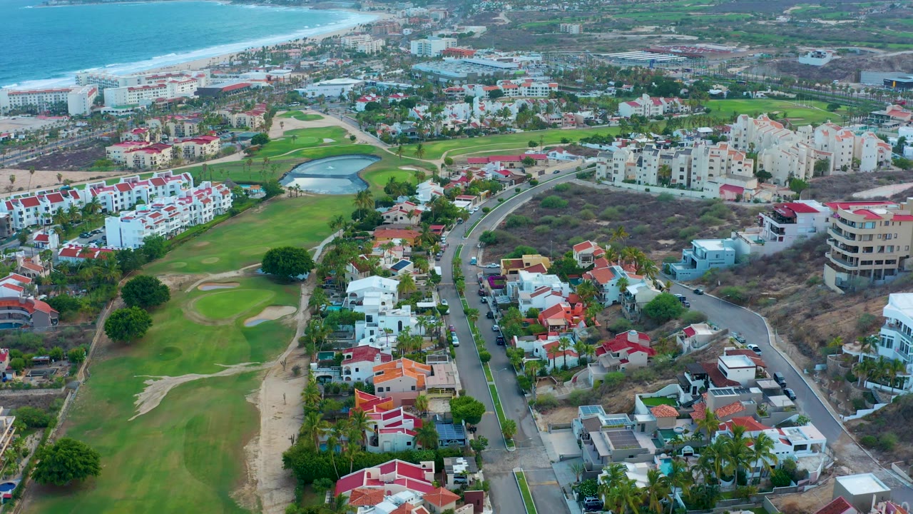 Golf course and residential blocks near a blue coastline.