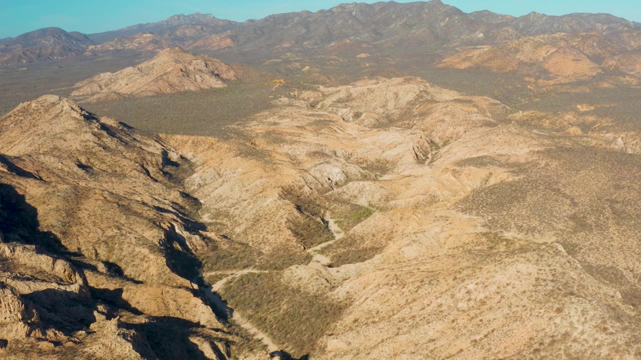 Dry mountain valley with ridges and shadowed foreground rock