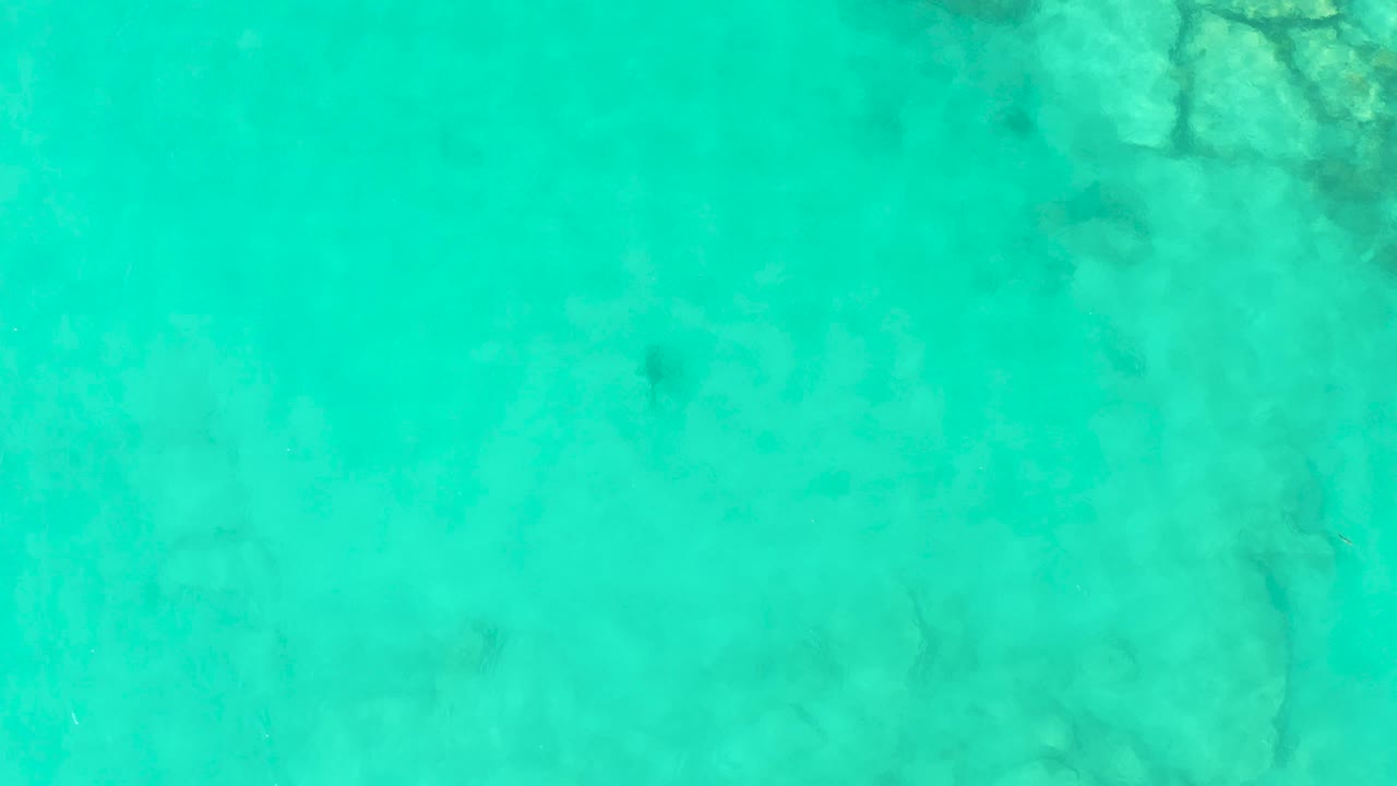 Clear green-blue water fills the frame above scattered submerged rocks in Cabo Pulmo, with no visible people or vessels.