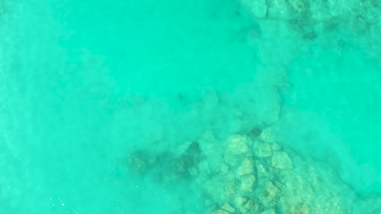 Turquoise water over submerged rocks.