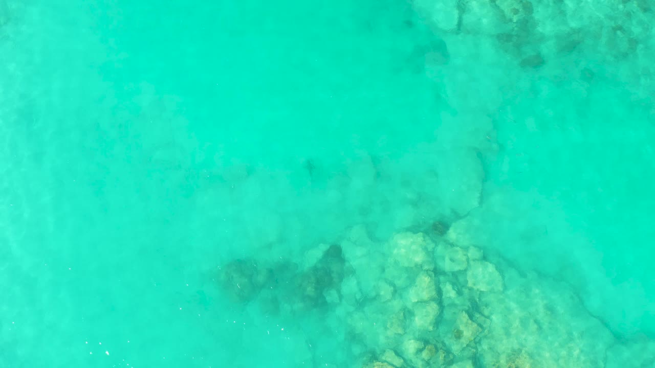 Clear blue-green water covers a rocky seabed patch near the lower part of the frame in Cabo Pulmo, with no visible people.