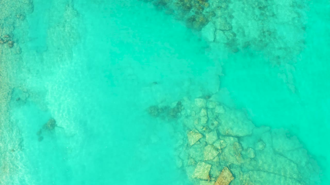 Aerial view of shallow turquoise water and underwater rocks