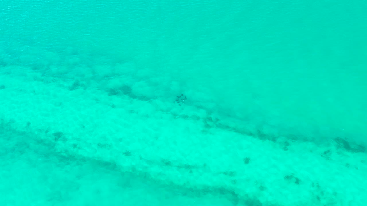 Turquoise shallow water over pale sandy seabed.