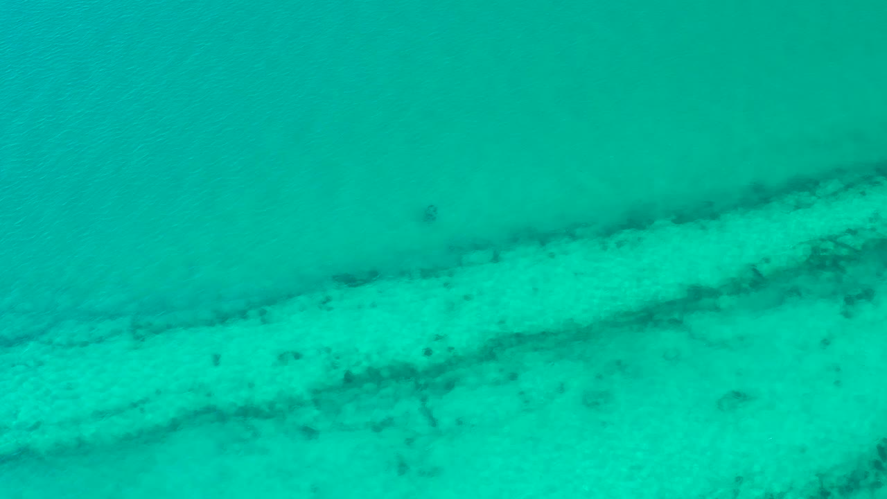 Overhead turquoise water with a diagonal pale seabed strip.