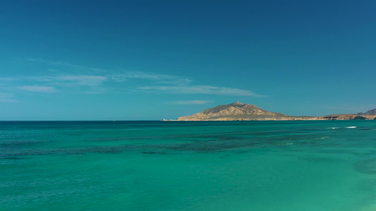 Turquoise ocean with distant island under blue sky