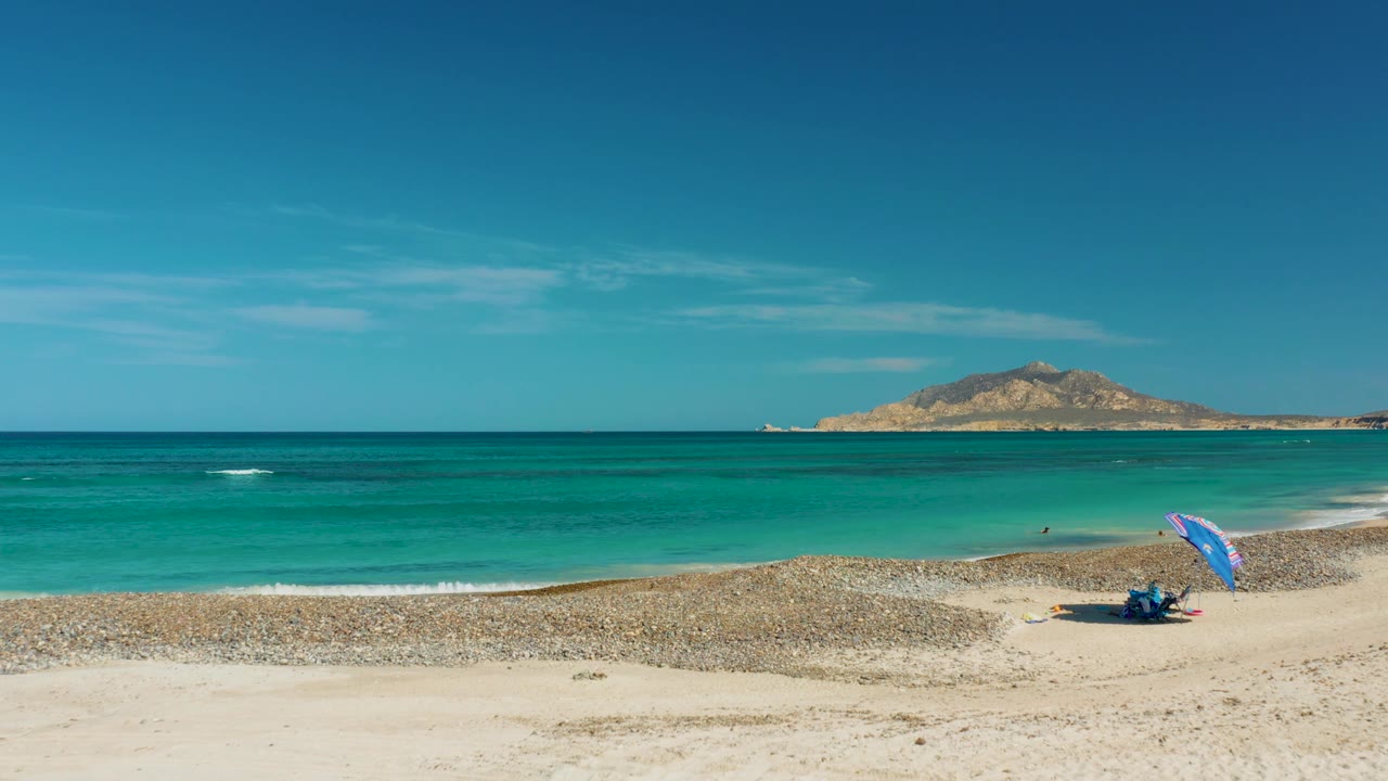 Turquoise shoreline with blue umbrella and distant island