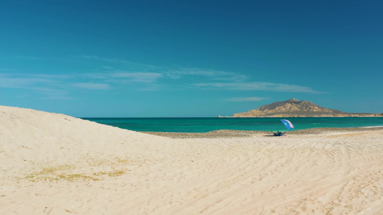 Wide beach view with dune foreground and calm turquoise ocean.