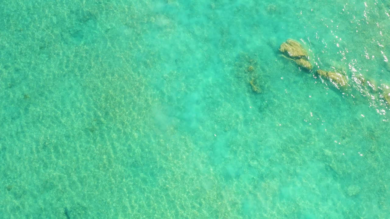 Submerged rocks in clear water with bright surface sparkle