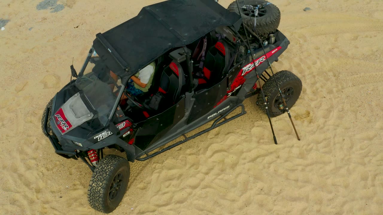 Overhead view of a black and red off-road buggy on sandy terrain in Laguna Beach Los Cabos, Baja California Sur, with tire marks around it and no visible people.
