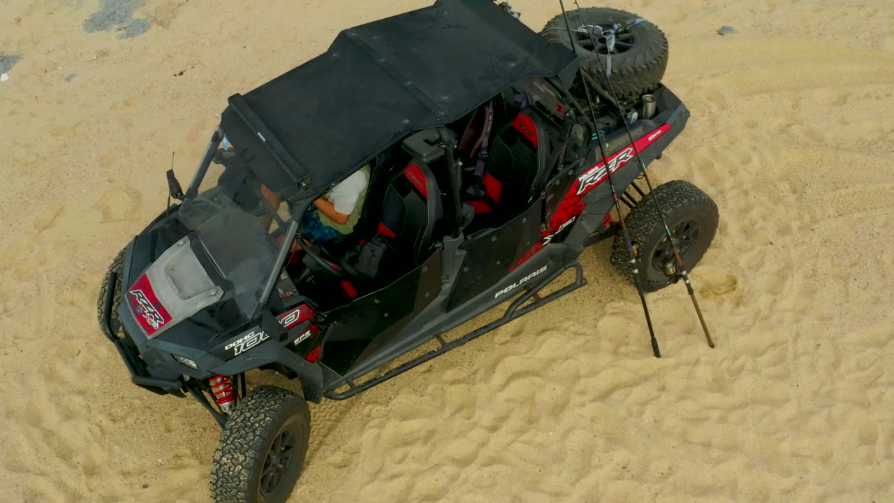 Open-top off-road buggy crossing pale sandy ground.