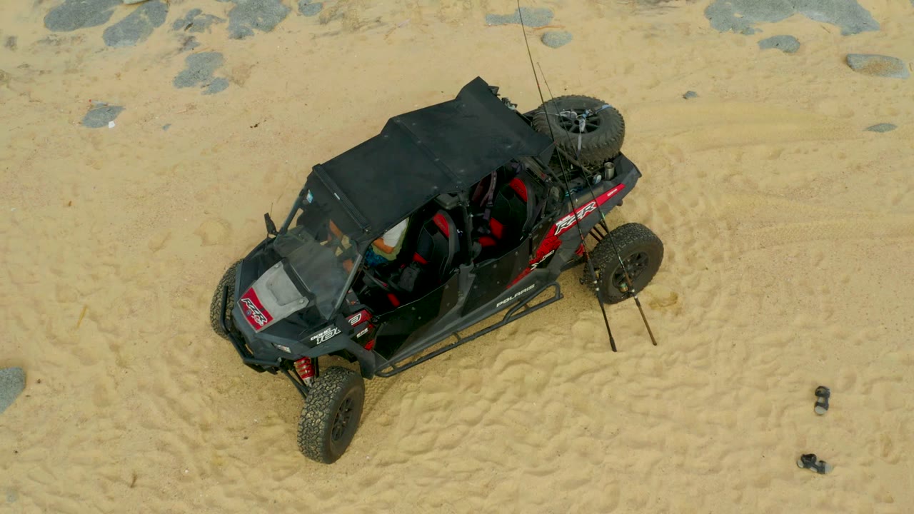 Dune buggy centered on tracked sand with scattered rocks