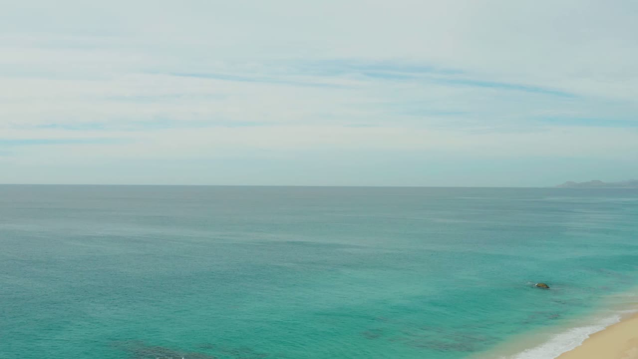Open turquoise sea with faint distant land and a sliver of beach.