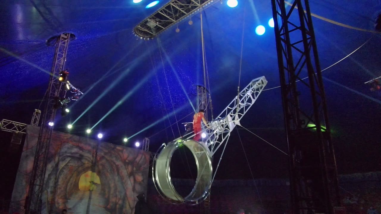 Aerial ring and truss tilted as the red-clad performer stands near the center.