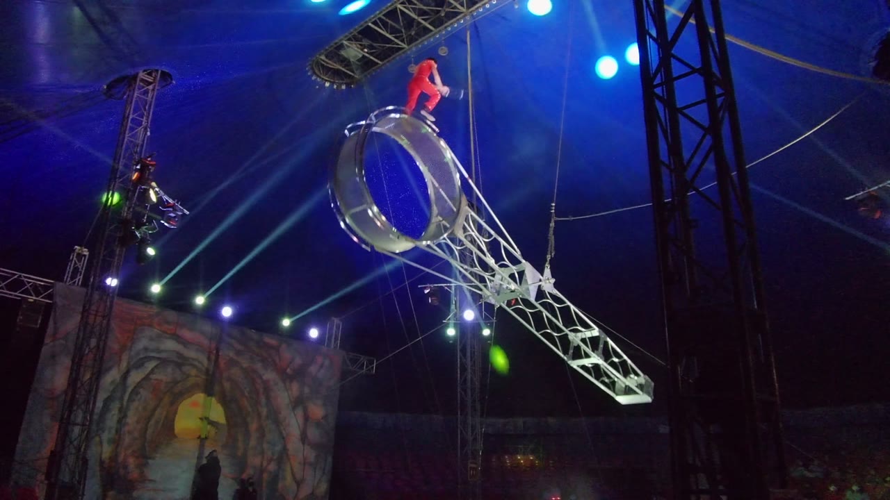 In San Jose Del Cabo, Mexico, the silver wheel is angled diagonally across the frame with the performer in red crouched near the top edge.